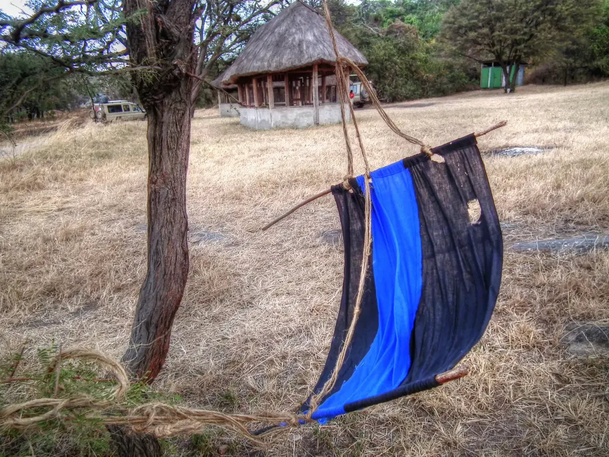 A blue and black cloth trap hanging from a tree in Tanzania, the type used to catch tsetse flies, a point to know about Serengeti safari packages